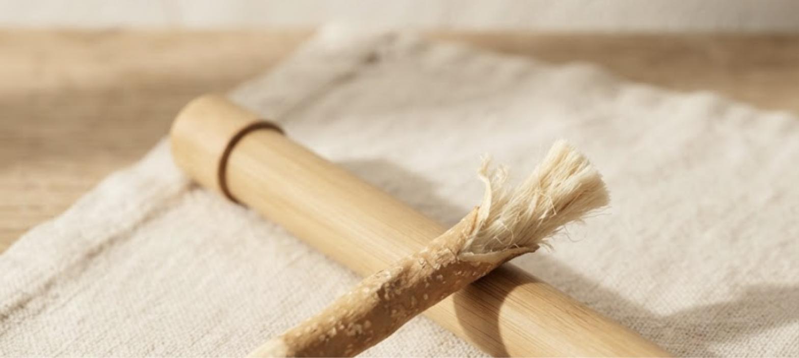 A single fresh miswak stick resting on a linen cloth beside its travel case